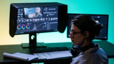 Focused video editor working at a dual-screen setup with colorful lighting ambiance.