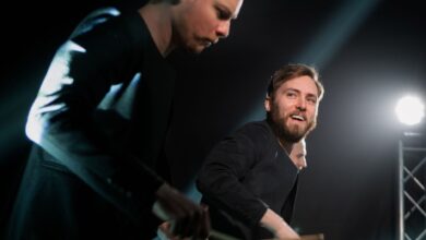 Dynamic drummers performing live on stage with focused lighting.