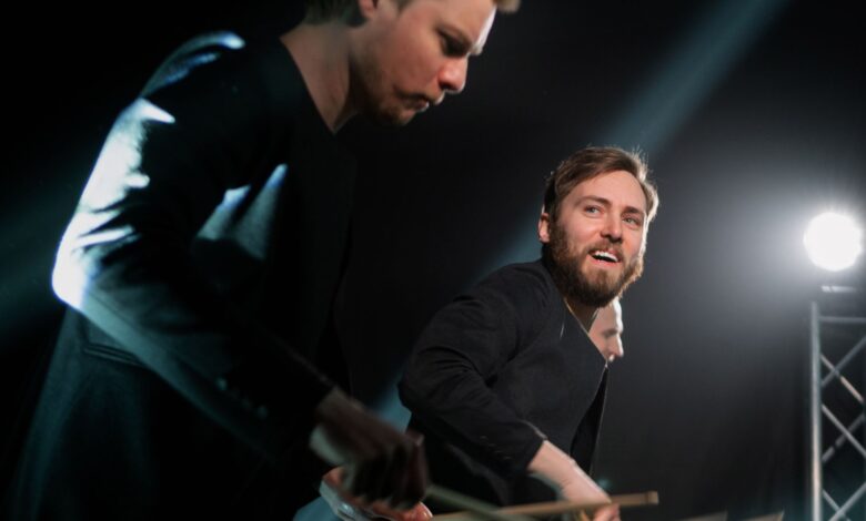 Dynamic drummers performing live on stage with focused lighting.