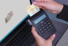 Person using contactless device for ID payment verification on a laptop.