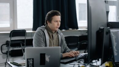 A dedicated programmer focused on coding at his workspace with dual monitors in a modern office setting.