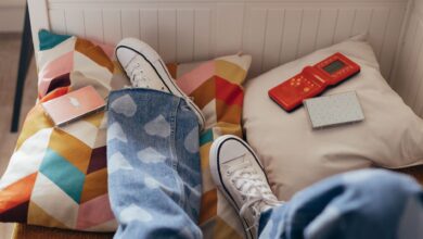 Teenager relaxes indoors with vintage games, colorful pillows, and casual jeans.
