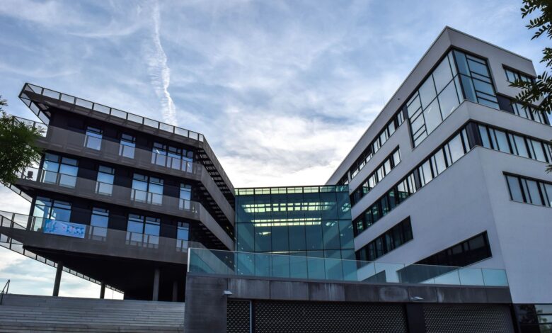 A modern glass-facade building against a blue sky, featuring innovative architecture.