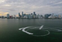 Aerial shot of Miami's skyline with watercraft patterns on the ocean surface.