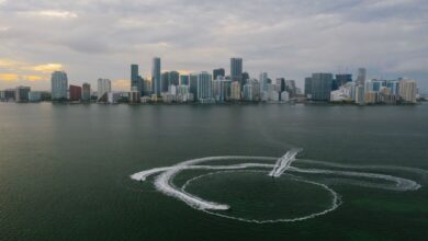 Aerial shot of Miami's skyline with watercraft patterns on the ocean surface.