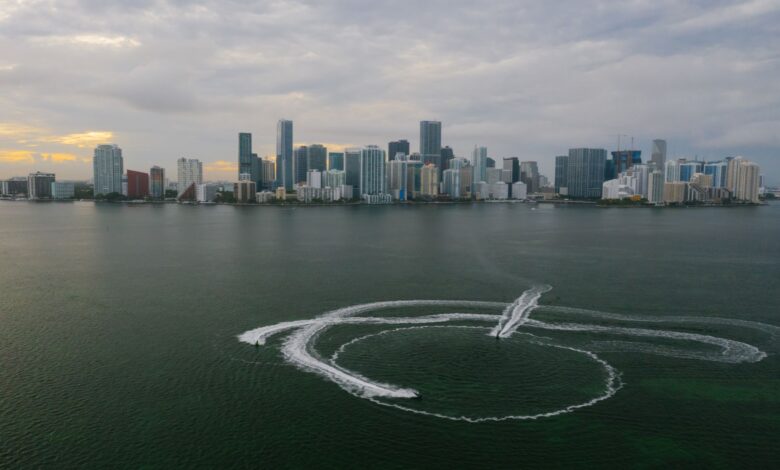 Aerial shot of Miami's skyline with watercraft patterns on the ocean surface.