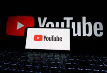 Close-up of YouTube logo displayed on a laptop screen in a dark environment.