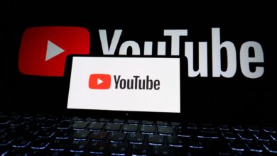 Close-up of YouTube logo displayed on a laptop screen in a dark environment.