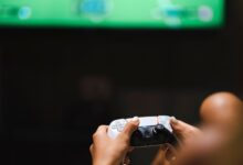 Close-up of hands holding a modern video game controller while gaming.