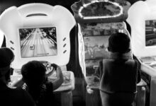 Black and white photo of children playing arcade games, creating a nostalgic feel.