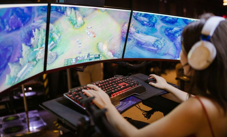 A young woman intently gaming on a multi-screen setup, showcasing vibrant gaming visuals.