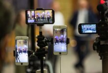 Multiple mobile phones capturing a live event at a prominent landmark in Oslo, Norway.