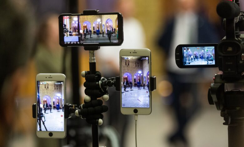 Multiple mobile phones capturing a live event at a prominent landmark in Oslo, Norway.