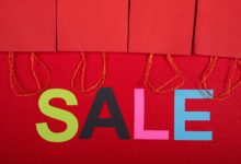Colorful sale sign with red shopping bags for retail promotions.