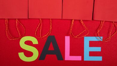 Colorful sale sign with red shopping bags for retail promotions.