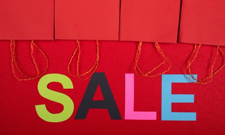 Colorful sale sign with red shopping bags for retail promotions.