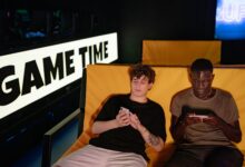 Two friends gaming on smartphones in a cozy indoor setting, enjoying leisure time together.