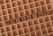 Wooden Scrabble tiles arranged to spell 'Phishing', illustrating online security concepts.