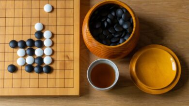 Top view of a Go board with black and white stones, tea, and bowls on a wooden surface.