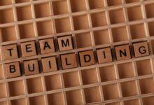Scrabble letters spelling 'TEAM BUILDING' on a wooden board symbolize teamwork and collaboration.
