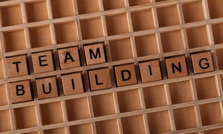Scrabble letters spelling 'TEAM BUILDING' on a wooden board symbolize teamwork and collaboration.