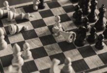 A monochrome vintage-style shot of a chess game in progress with scattered pieces.