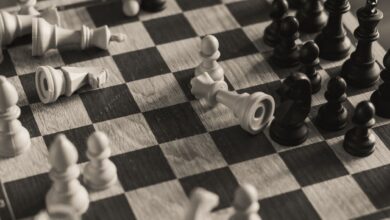 A monochrome vintage-style shot of a chess game in progress with scattered pieces.
