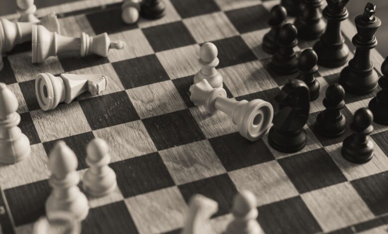 A monochrome vintage-style shot of a chess game in progress with scattered pieces.