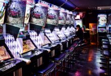 A man plays inside a modern arcade in Tokyo, illuminated by neon lights and gaming machines.