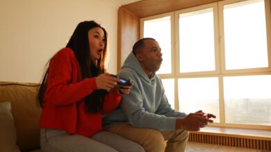 A couple engaged in playing video games, sitting on a sofa in a cozy living room setting.