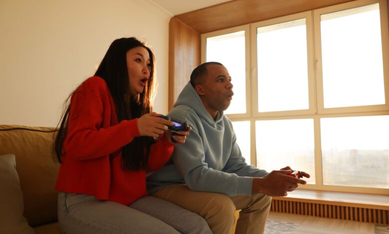 A couple engaged in playing video games, sitting on a sofa in a cozy living room setting.