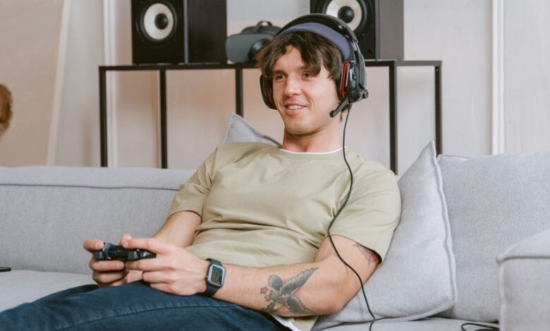 Young man enjoying video gaming session at home with a headset and controller.