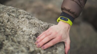 Close-up of a hand with a fitness tracker touching a rock outdoors, showcasing exploration.