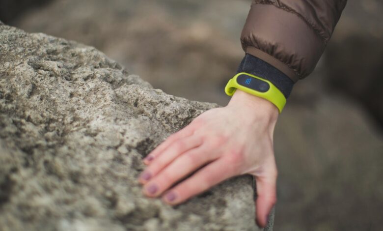 Close-up of a hand with a fitness tracker touching a rock outdoors, showcasing exploration.