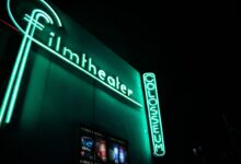 Vibrant neon film theater sign glowing at nighttime.