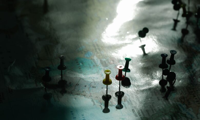 A map with colored pins under dramatic light, highlighting travel planning and destinations.