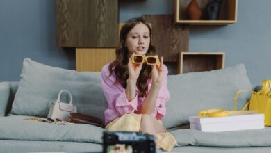 Young woman showcasing trendy sunglasses on a video blog at home.