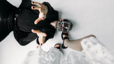 A captivating photoshoot featuring a man with skull makeup in a dynamic pose on a studio floor.