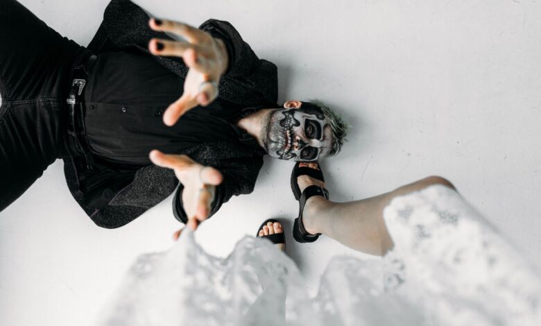 A captivating photoshoot featuring a man with skull makeup in a dynamic pose on a studio floor.