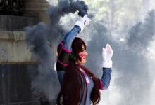A cosplayer dressed in detailed costume poses with smoke in an outdoor setting. Stylish and dynamic scene.