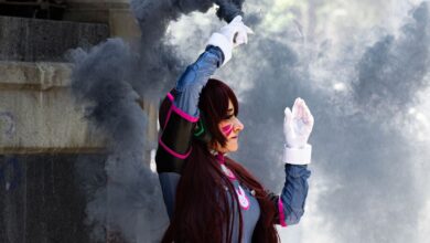 A cosplayer dressed in detailed costume poses with smoke in an outdoor setting. Stylish and dynamic scene.