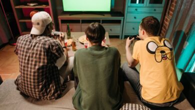 Three young men enjoying a home gaming session together, playing video games in a cozy indoors setting.