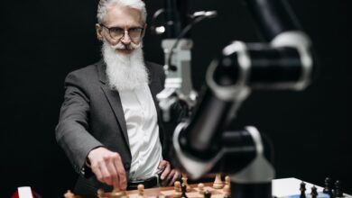 An older man engages in a strategic chess game with a robotic arm, illustrating the blend of tradition and technology.