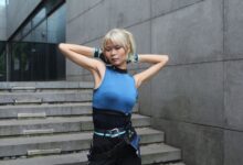 Cosplayer posing outdoors in a modern urban environment, striking a confident pose.
