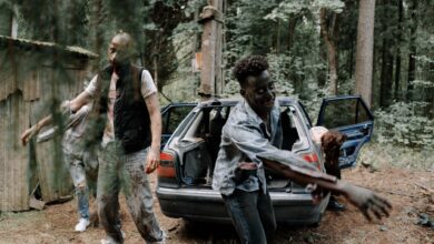A group of zombies walking near an abandoned car in a creepy forest setting.