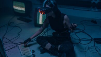 A woman in a VR headset and gloves interacts with technology in a dimly lit room.