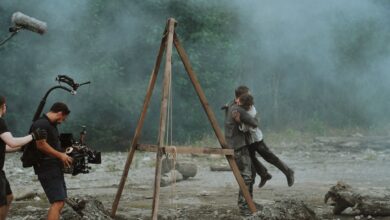 Cinematic embrace captured on a film set amidst smoke outdoors.
