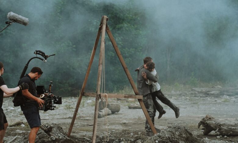 Cinematic embrace captured on a film set amidst smoke outdoors.