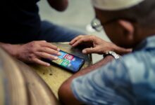 Two individuals play a mobile game on a smartphone outdoors in Jakarta, Indonesia.