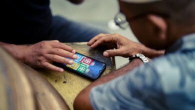 Two individuals play a mobile game on a smartphone outdoors in Jakarta, Indonesia.